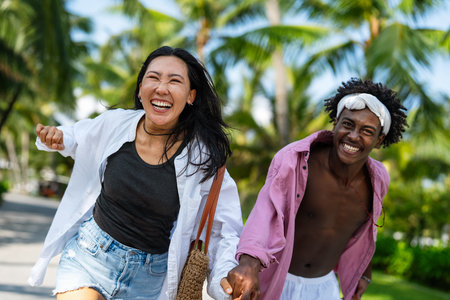 Romantic interracial couple enjoying a tropical honeymoon on a beach, embracing love and happinessの写真素材