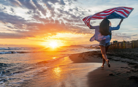 Happy woman running on beach while celebrating independence day and enjoying freedom in USAの写真素材