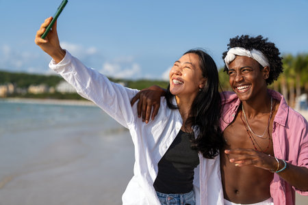 Influencer couple taking selfie on tropical beach, enjoying vacation, social media content creationの写真素材