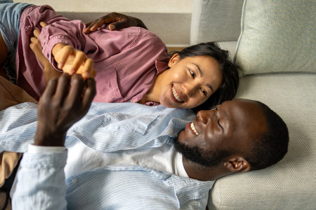 Happy multiethnic couple, love and hug laughing in joyful happiness for bonding time togetherの写真素材