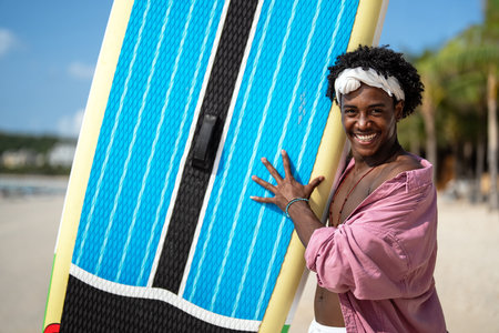 Young Black man enjoying a sunny beach day, running through ocean waves, smiling and feeling free