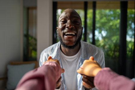 Young diverse couple joyfully smiling together in their bright living room, wearing casual clothesの写真素材