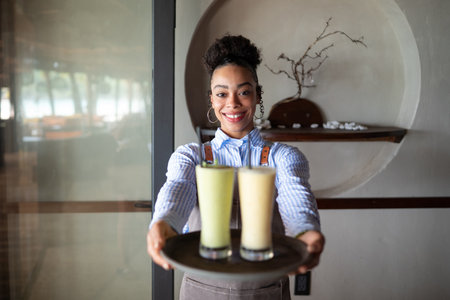 Waitress with smoothies on a tray in a stylish eatery offering friendly service and a cozy vibeの写真素材