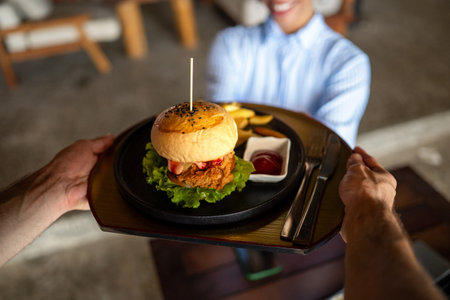 Waiter serves a fresh burger and fries in stylish restaurant, capturing the essence of great service