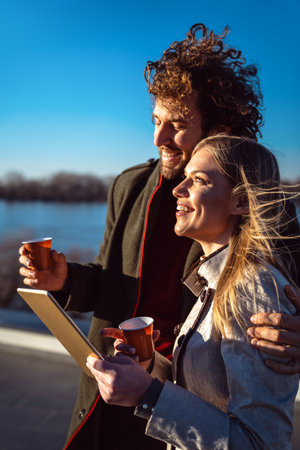Happy couple outdoors using tablet together, enjoying sunny day, love, connection, digital lifestyle