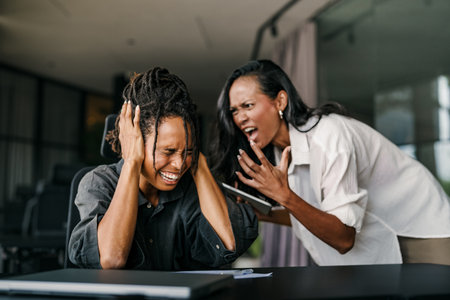 Stressful work environment. Frustrated boss yelling at his subordinate in the officeの写真素材