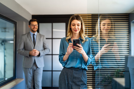 In a modern office, a successful businesswoman multitasks with phone communicationの写真素材