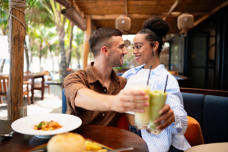 Romantic dining moments, a smiling man enjoys a special meal while holding hands with his partnerの写真素材