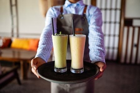 Waitress with smoothies on a tray in a stylish eatery offering friendly service and a cozy vibeの写真素材