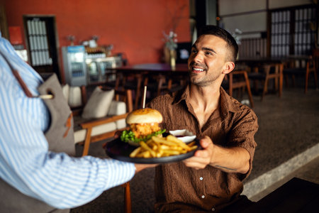 Waitress delivers a juicy burger in cozy restaurant setting with a warm smile and great hospitalityの写真素材