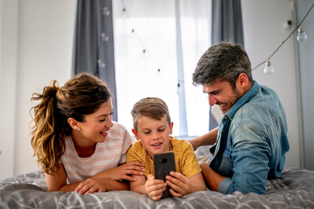 Happy family and kid having fun with smartphone, digital gadget at home. People, technologyの写真素材