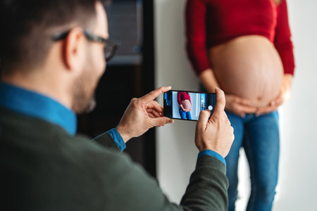 Pregnant woman with her husband taking photos. Happy couple who cant wait to become parents