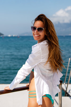 Happy woman embracing summer lifestyle with joy and confidence on a boat, smiling on tripの写真素材