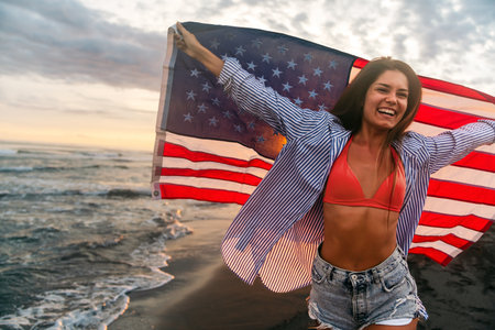 Happy woman running on beach while celebrating independence day and enjoying freedom in USAの写真素材