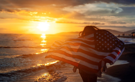 Happy woman running on beach while celebrating independence day and enjoying freedom in USAの写真素材