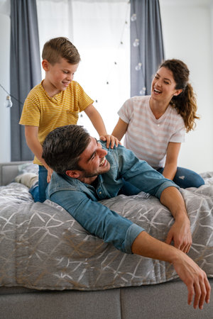 Family from three people cheerfully spends fun time at home together. Parents, kid happiness conceptの写真素材