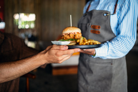 Waiter serves a fresh burger and fries in stylish restaurant, capturing the essence of great serviceの写真素材
