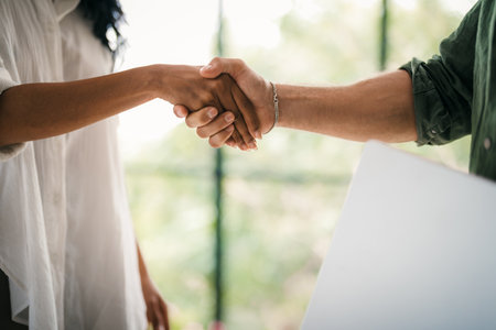 Handshake of happy young business woman and business man at office meetingの写真素材