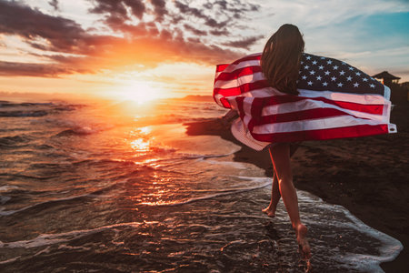 Happy woman running on beach while celebrating independence day and enjoying freedom in USAの写真素材