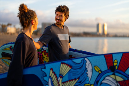 Two young people, friends with surfboard, going for surfing in the sea. Surfers carrying surfboards