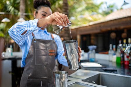 A young african american woman bartender works in a bar made a cocktail on summer vacationの写真素材