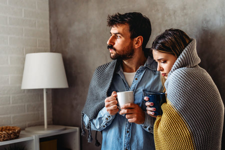 Freezing man and woman suffering from cold or flu fever or having trouble with central heating