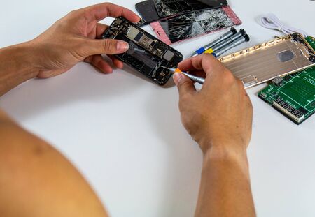 The repairman is bringing out the mobile phone's charging port. Before putting the new charger port into placeの写真素材