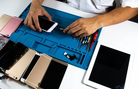 The repairman tightens the nut to fix the mobile phone.の写真素材