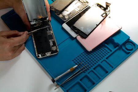 The mobile repairman is removing the mobile phone screen in order to replace the damaged parts from being dropped.の写真素材