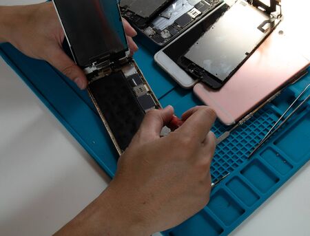 At the mobile phone mechanic's desk He is disassembling the mobile phone To check for damage caused by droppingの写真素材