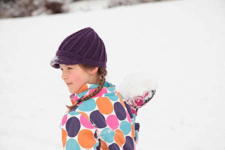 A girl with a snowball in her hand, about to throw itの写真素材