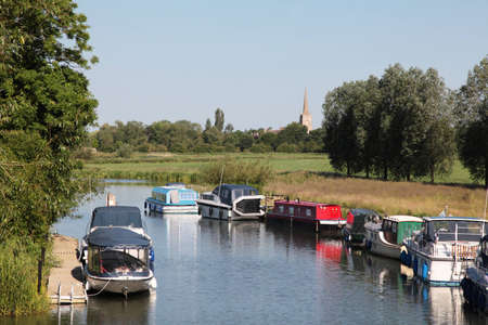 Boats moored on a river with a cathedral in the distanceの写真素材