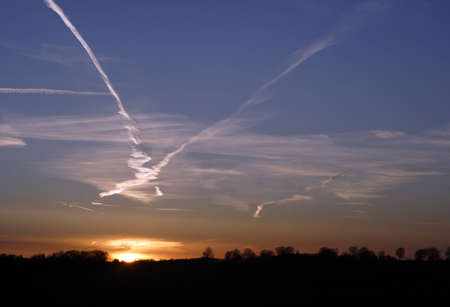Jet trails crossing at sunsetの写真素材