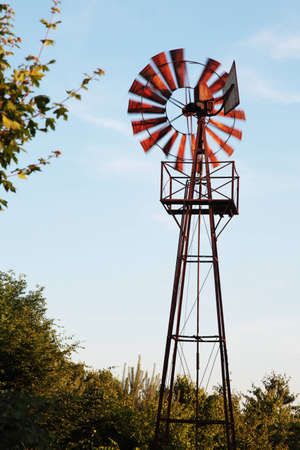 An old rusty windmill spinning in the wind, the blades are motion blurredの写真素材