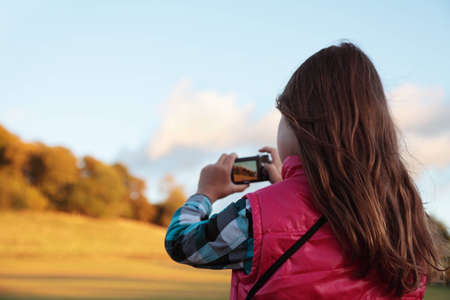 A young girl viewing a forrest at sunset in her viewfinderの写真素材