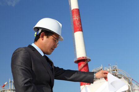 industrial engineer checking plan on location site with tower and blue sky backgroundの写真素材
