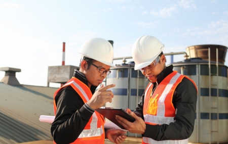 two engineer oil industry discussing a new project with large oil refinery background の写真素材