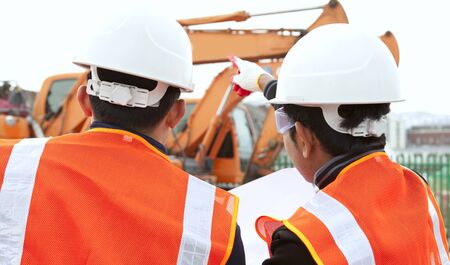 two construction worker discussion on construction site with excavator on the backgroundの写真素材
