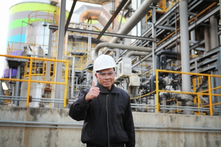 industrial engineer with thumbs up standing beside pipeline inside oil refineryの写真素材