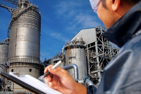 engineer oil refinery write on the notes book looking large oil refinery focus on refineryの写真素材