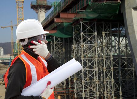Engineer On A Construction Site Using A Mobile Cellphone の写真素材