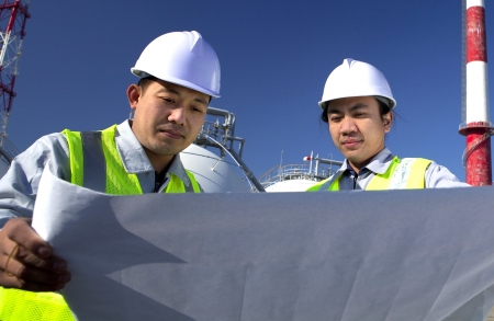oil gas industrial engineer checking plan with storage tank and tower on the backgroundの写真素材