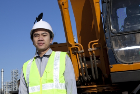portrait construction worker standing front of heavy equipmentの写真素材