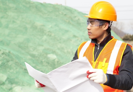 Construction worker with blueprint on construction siteの写真素材