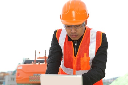 road construction worker using laptop standing front excavatorの写真素材