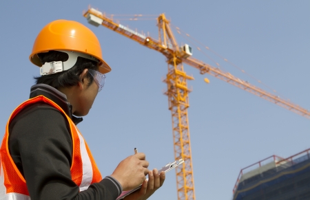 construction worker checking a document with crane on the backgroundの写真素材