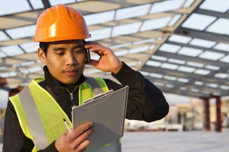 Engineer construction talking mobile phone under new building の写真素材