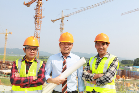 Group of workers and manager standing under craneの写真素材