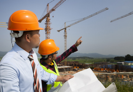 Builder workers partners looking at new construction plan and discussing itの写真素材