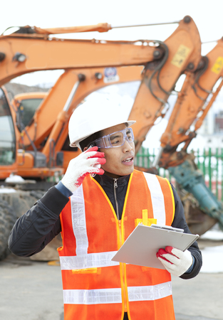 Construction worker talking on the phone and holding clipboardの写真素材